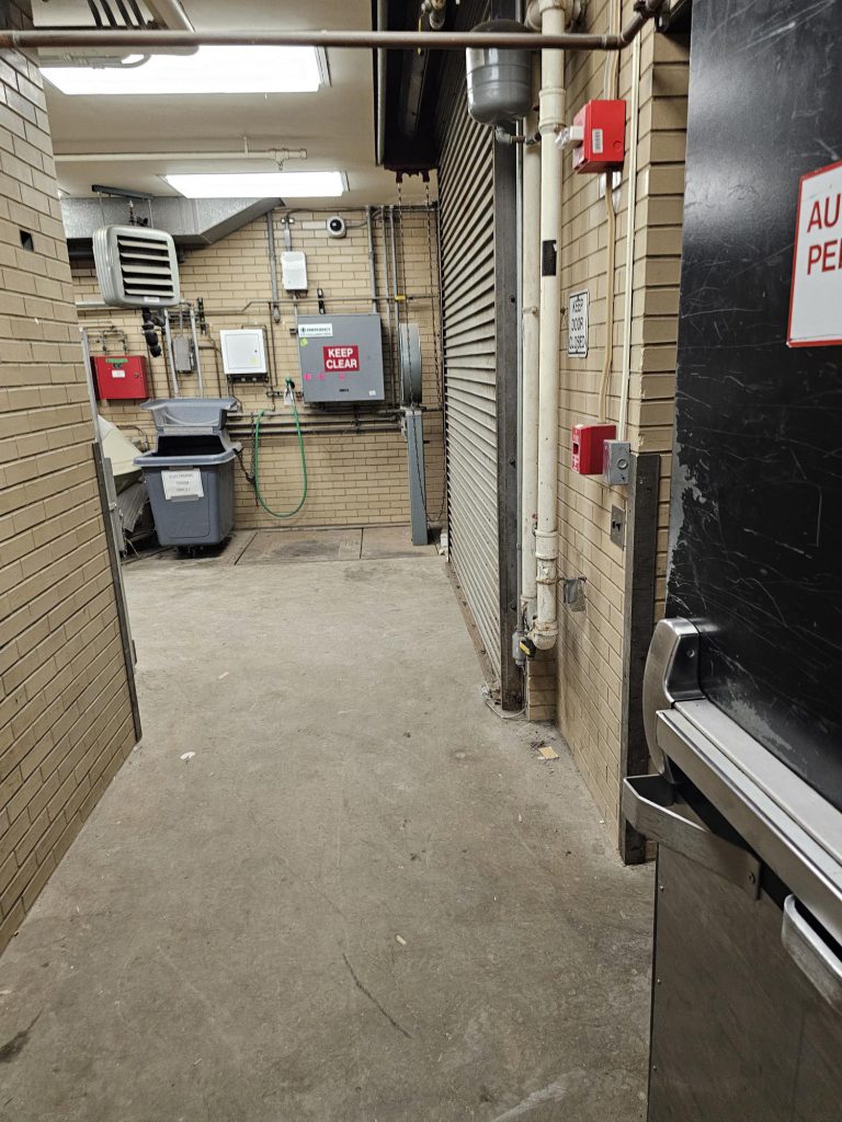 Inside of the Chevron loading dock, showing eyewash, roll up door and the electronics trash bin.